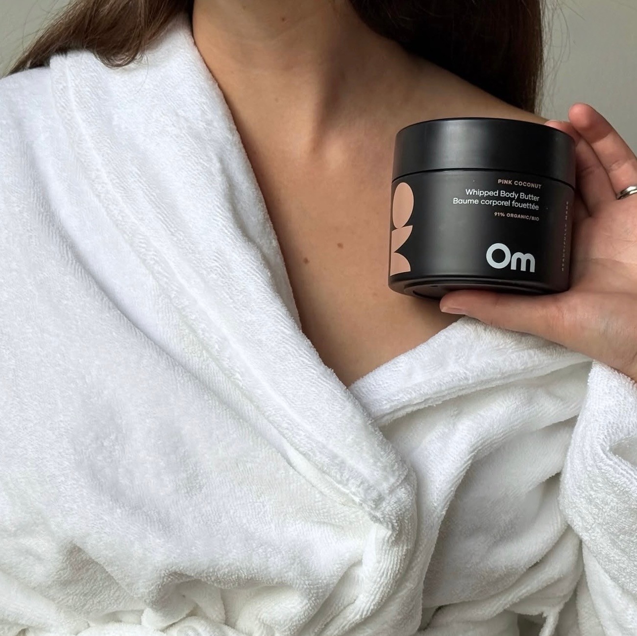 Shot of a woman in a white robe holding up an Om jar