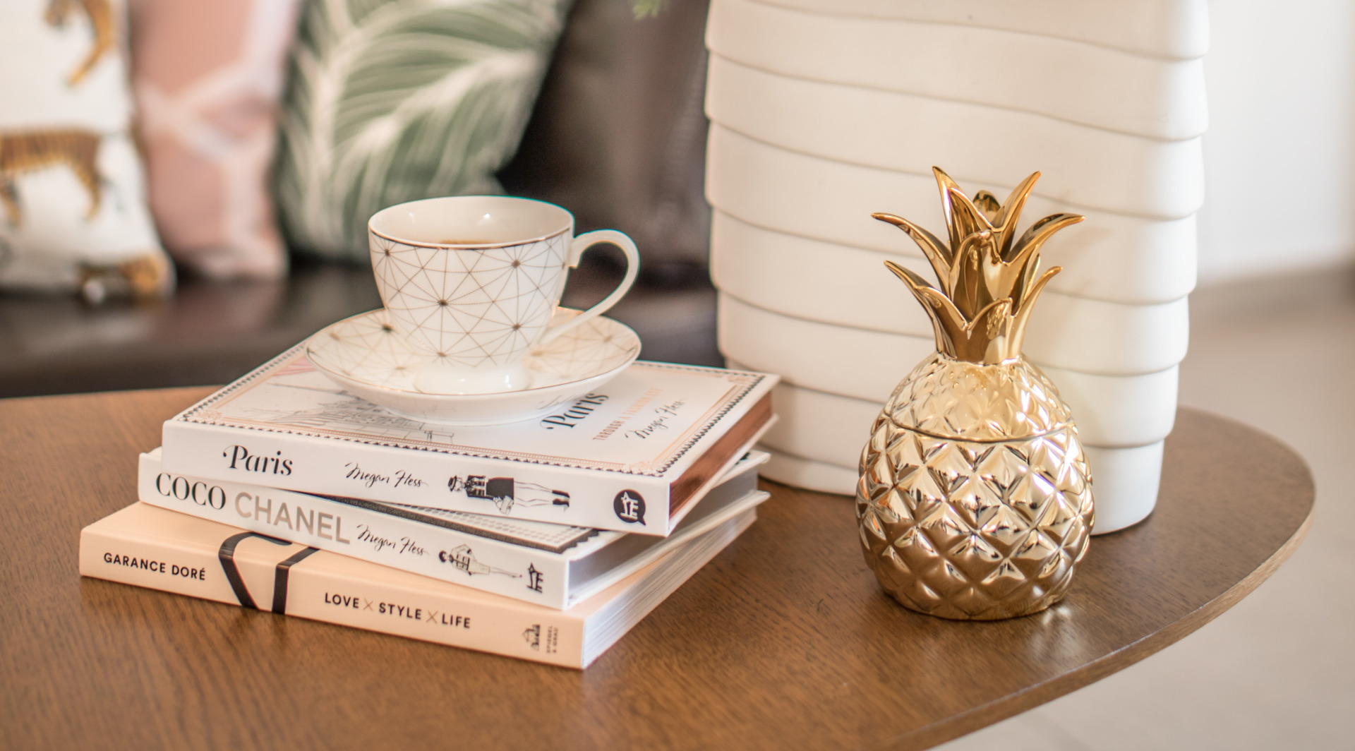 The Annex Careers banner closeup of home decor on a wood coffee table, including a gold pineapple holder and fashion books